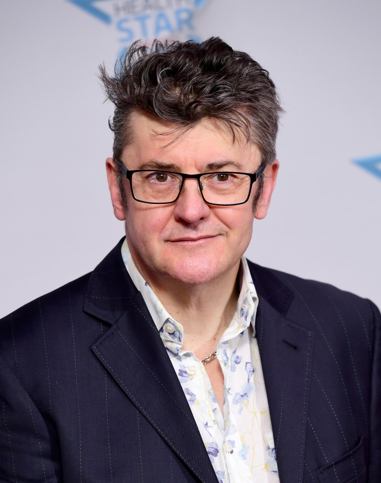 a man wearing glasses and a suit stands in front of a sign that says best star