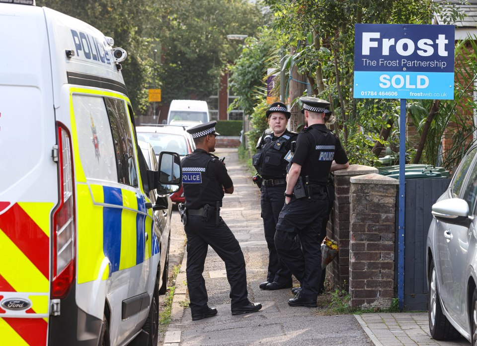 a group of police officers standing in front of a frost partnership sold sign