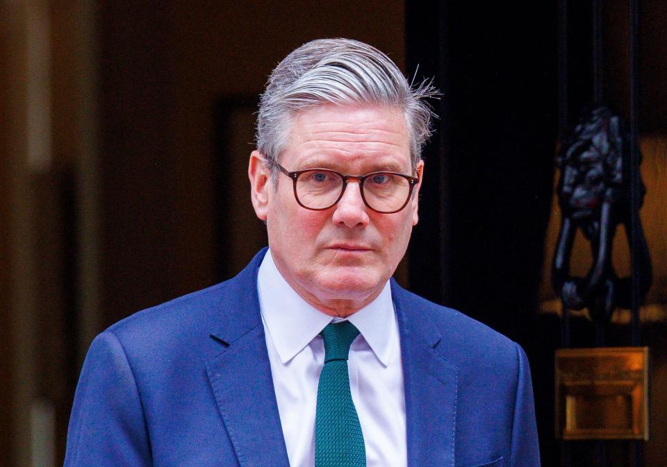 a man wearing glasses and a blue suit stands in front of a door