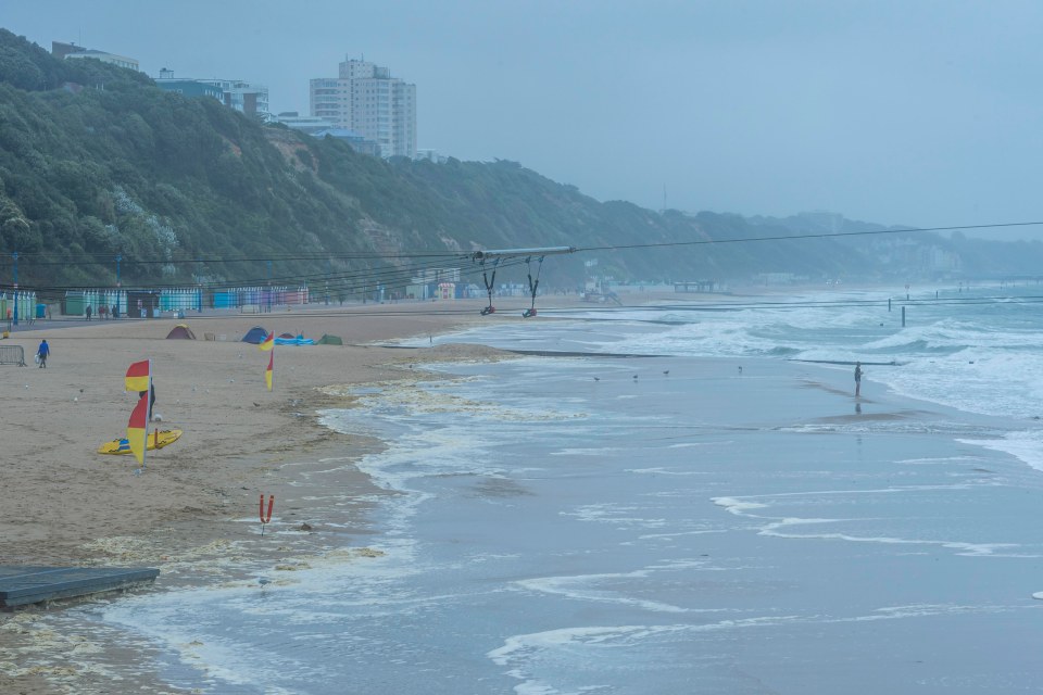 a beach with a red yellow and blue sailboat