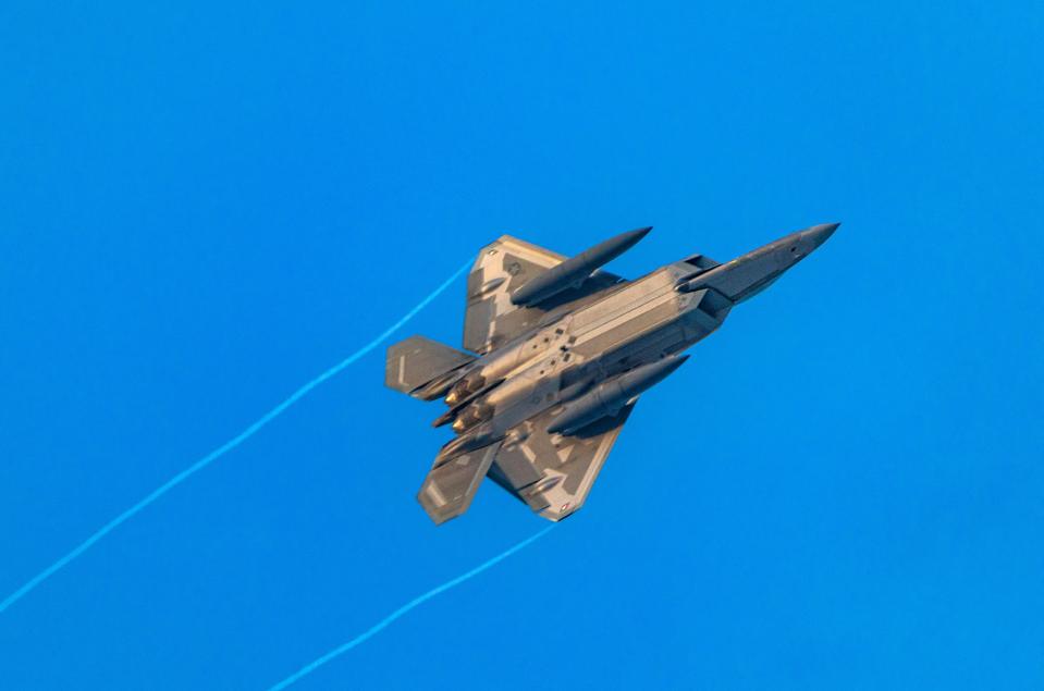 a fighter jet is flying through a clear blue sky