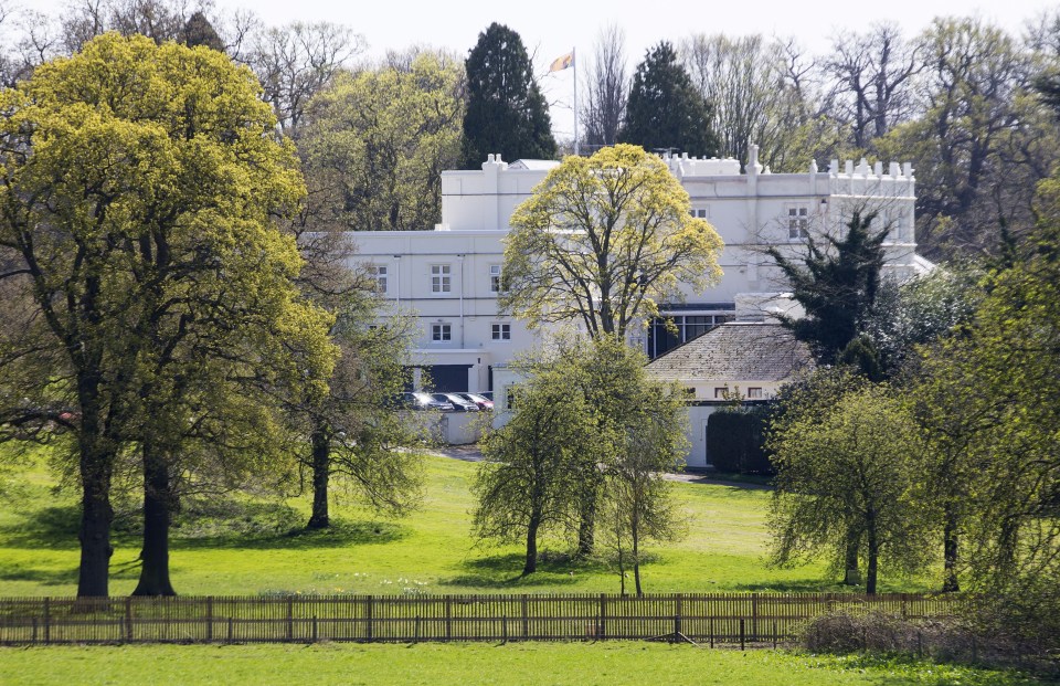a large white building is surrounded by trees and a fence