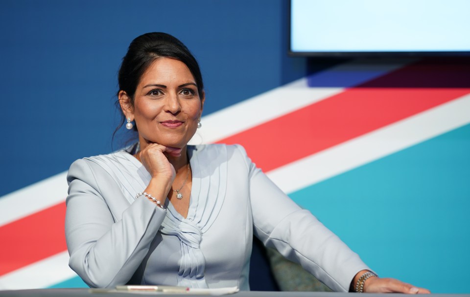 a woman sits at a table in front of a british flag