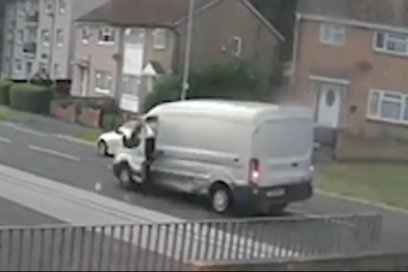 a white van is parked on the side of the road next to a fence .
