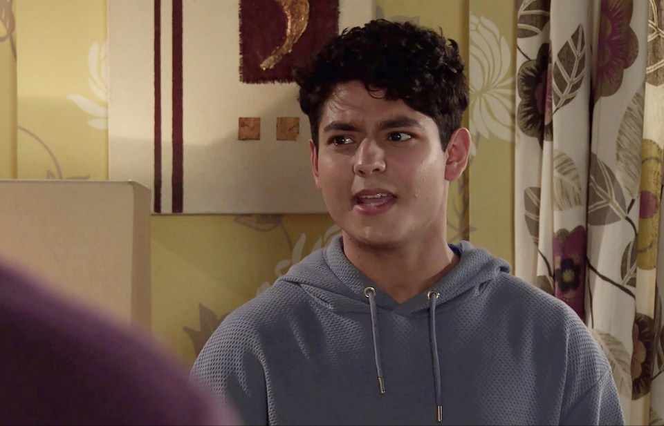 a young man in a blue hoodie looks at another man