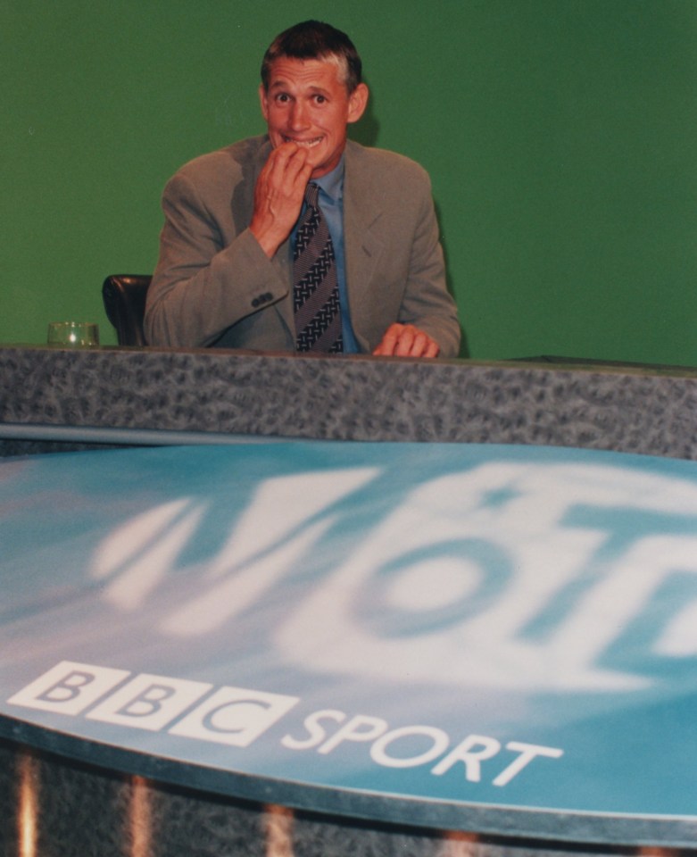 a man sitting at a desk with a sign that says bbc sport