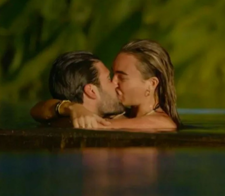 a man and a woman are kissing in a swimming pool .