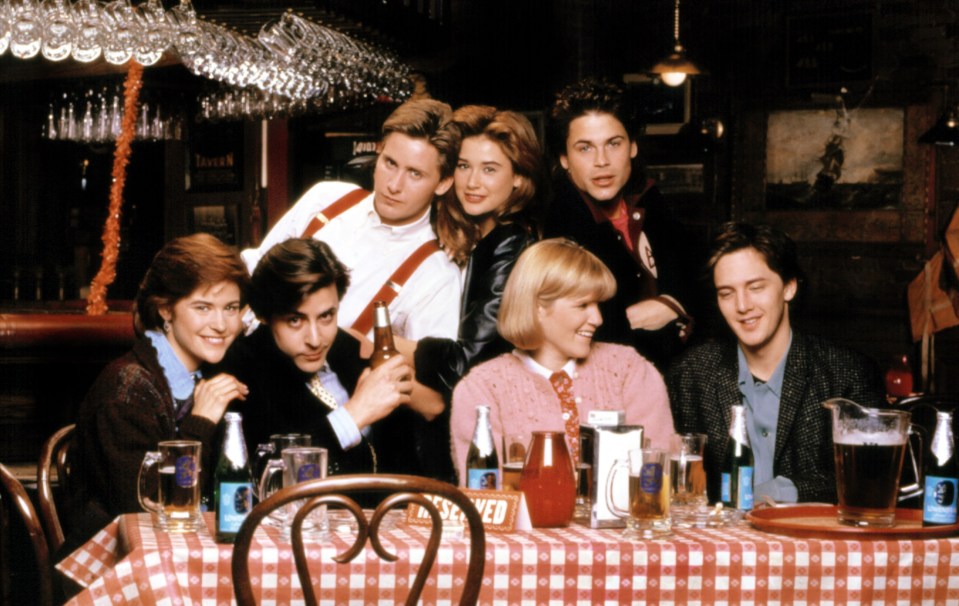 a group of people sitting around a table with a red and white checkered table cloth
