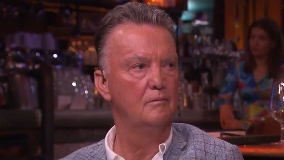 a man in a suit and white shirt is sitting at a table in a bar .