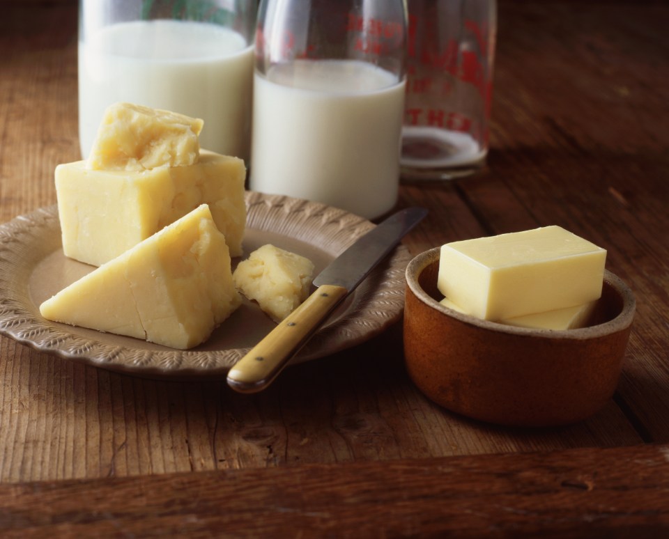 a plate of cheese butter and milk on a wooden table