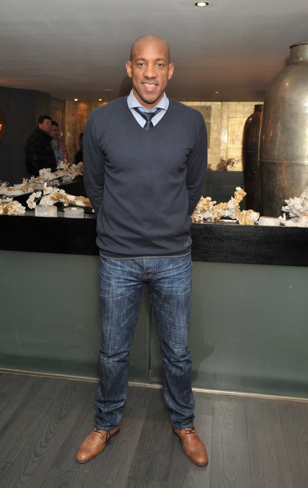 a man wearing a sweater and tie is standing in front of a counter