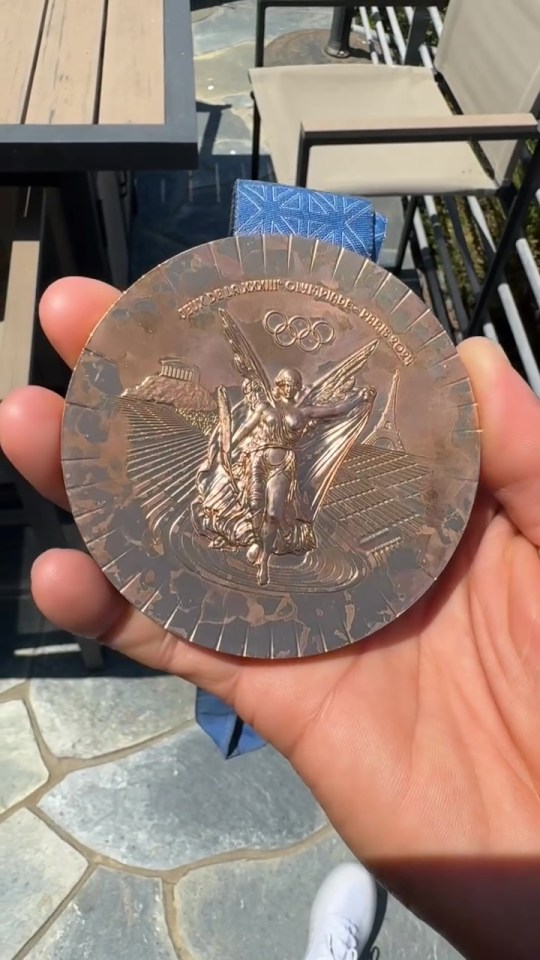 a person holding a medal that says olympics on it