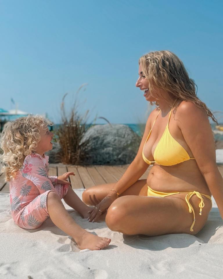 a woman in a yellow bikini sits next to a little girl