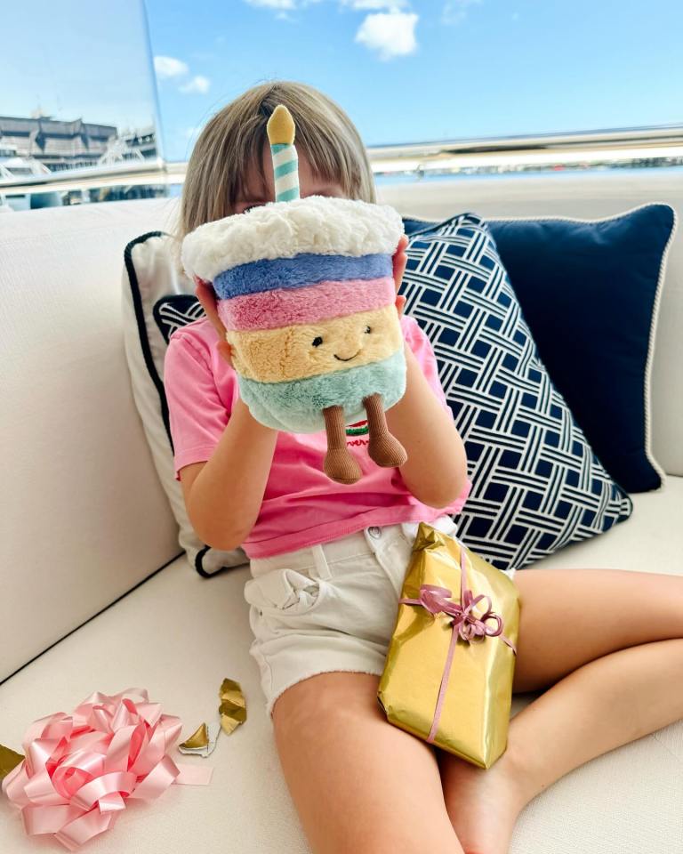 a little girl is holding a stuffed birthday cake