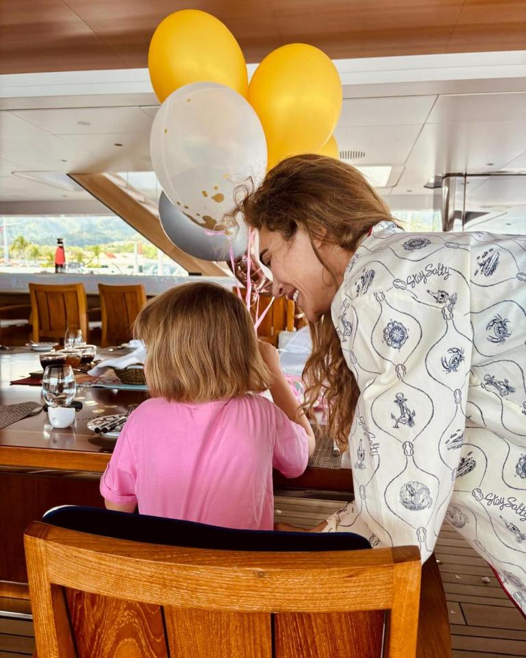 a woman and a little girl are playing with balloons on a boat