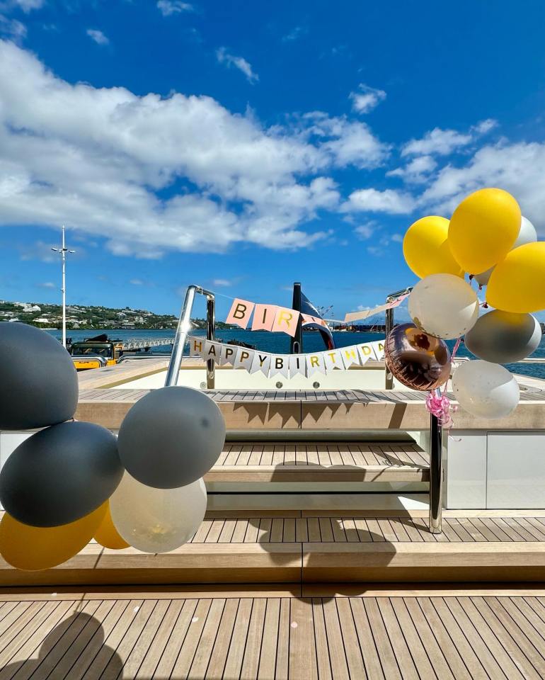 a boat with balloons and a happy birthday banner