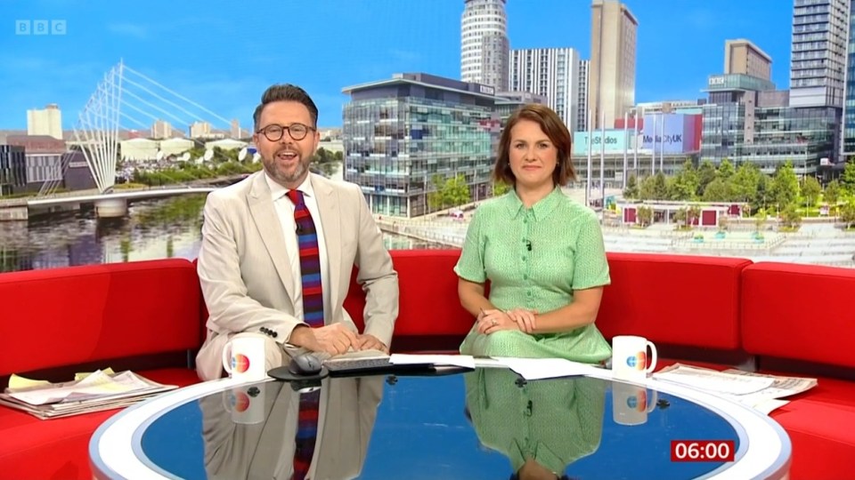 a man and a woman sit in front of a bbc logo