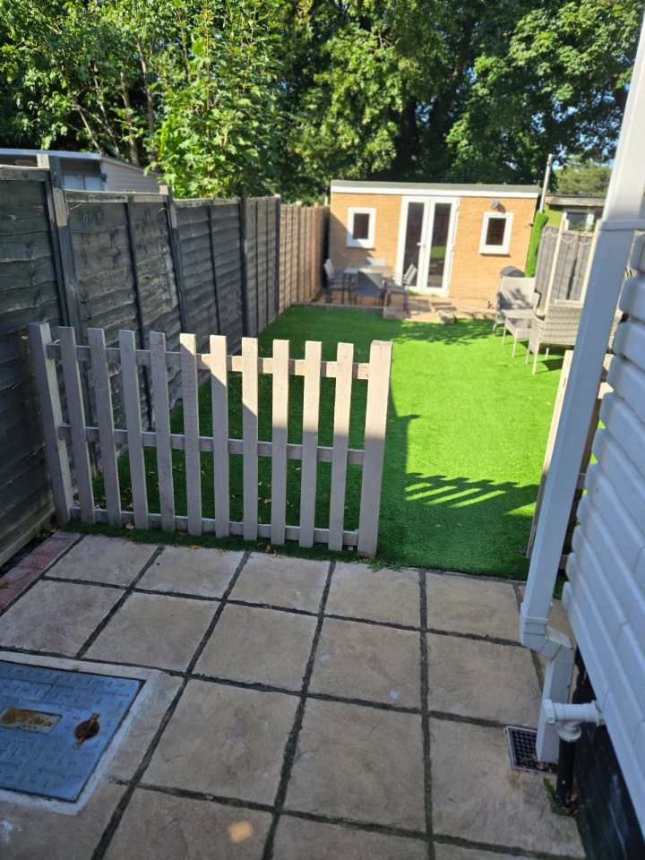 a white picket fence surrounds a lush green backyard