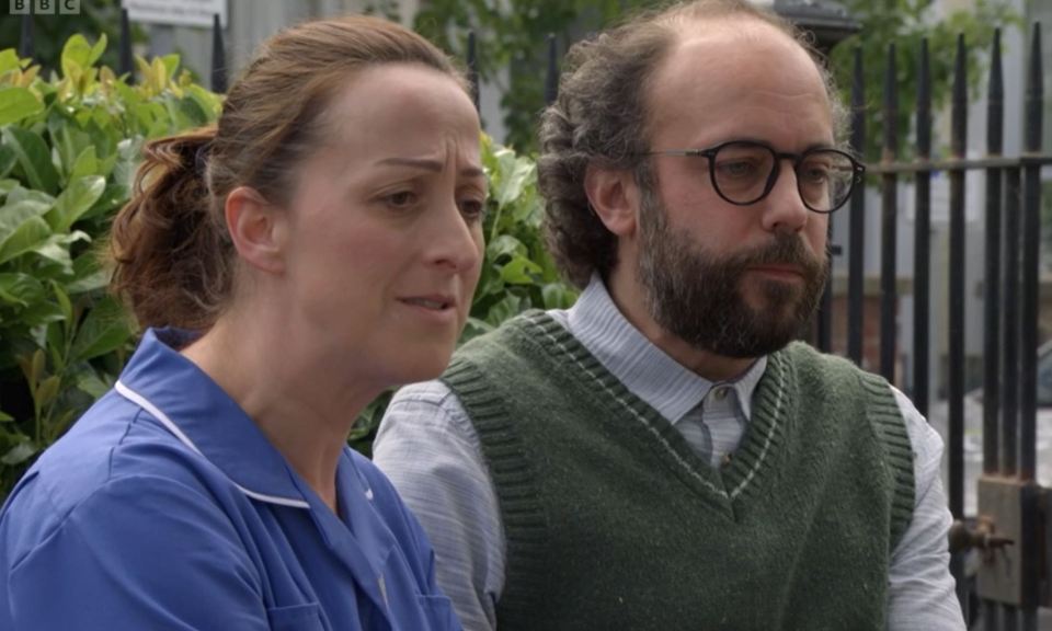 a man and a woman are sitting in front of a bbc sign