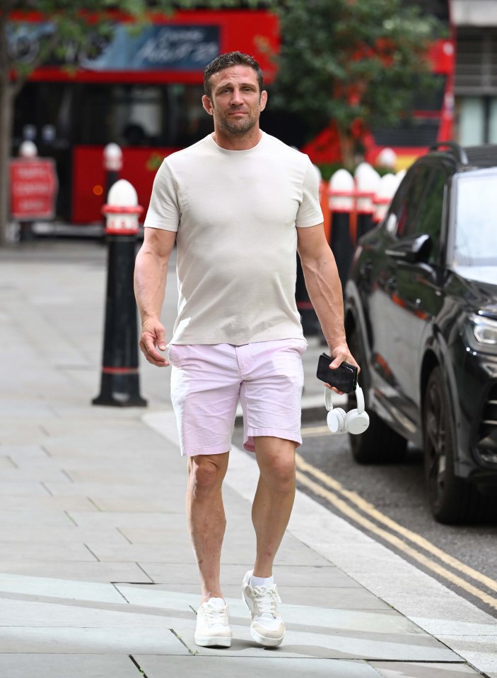 a man in a white shirt and pink shorts walks down the street