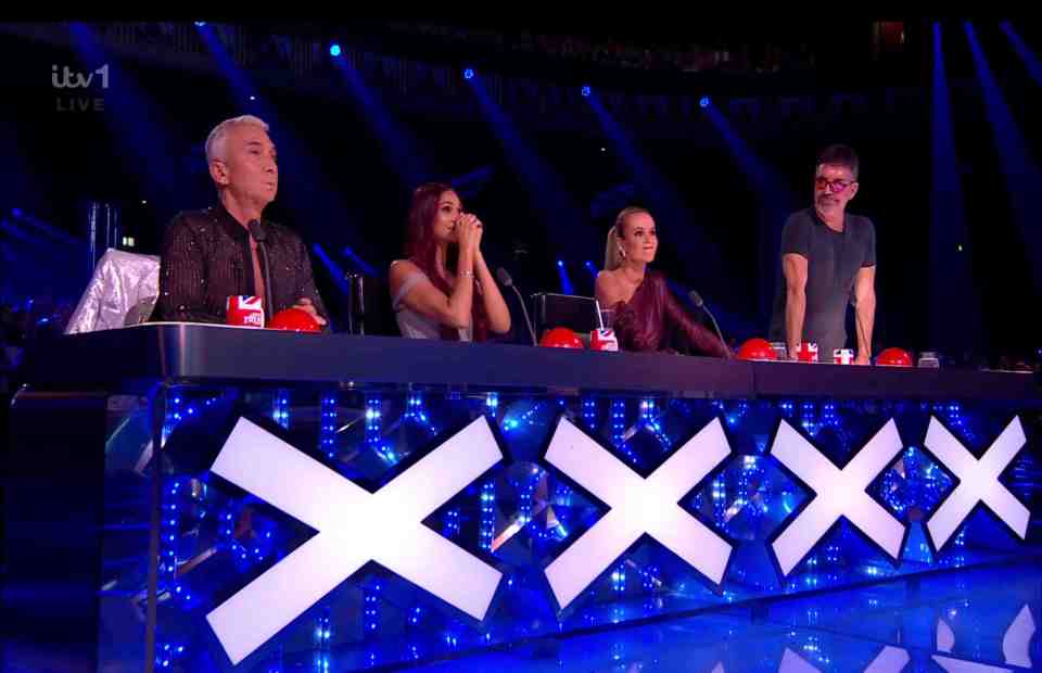 a group of judges sit at a table with an x on it