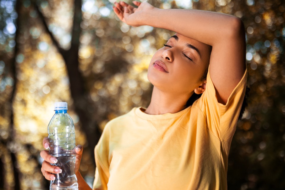 a woman in a yellow shirt is holding a bottle of water