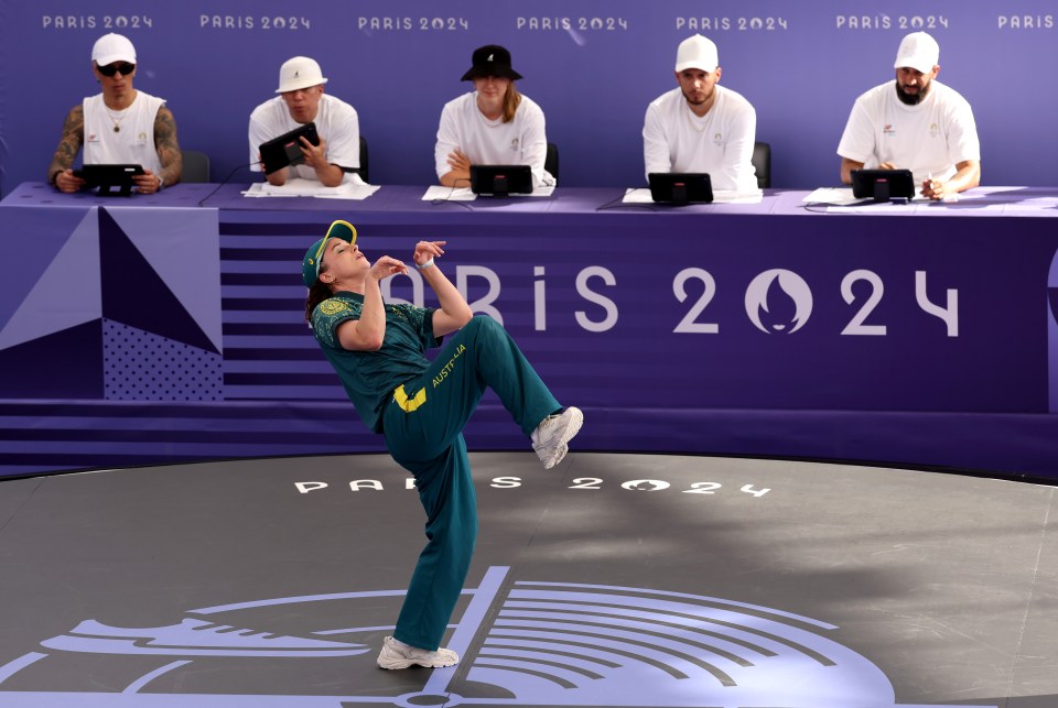 a man performs in front of a paris 2024 sign