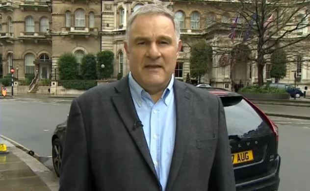 a man in a suit and blue shirt is standing in front of a car on a street .