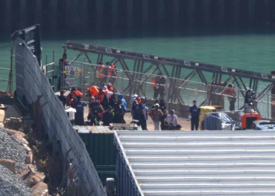 a group of people are gathered near a fence with a sign that says no entry