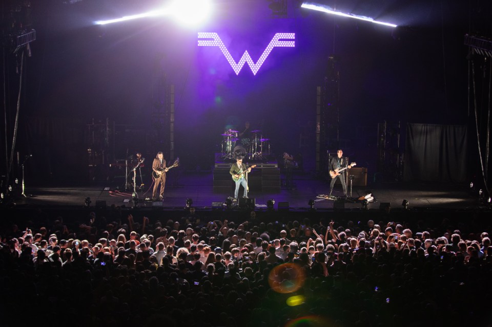 a band performs on stage with a large w in the background