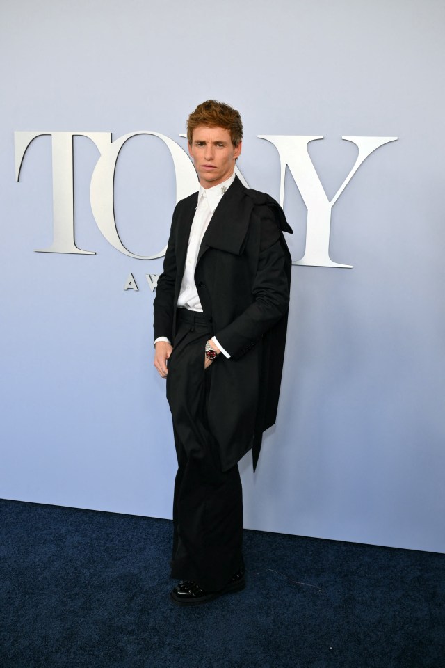 a man in a tuxedo stands in front of a sign that says tony