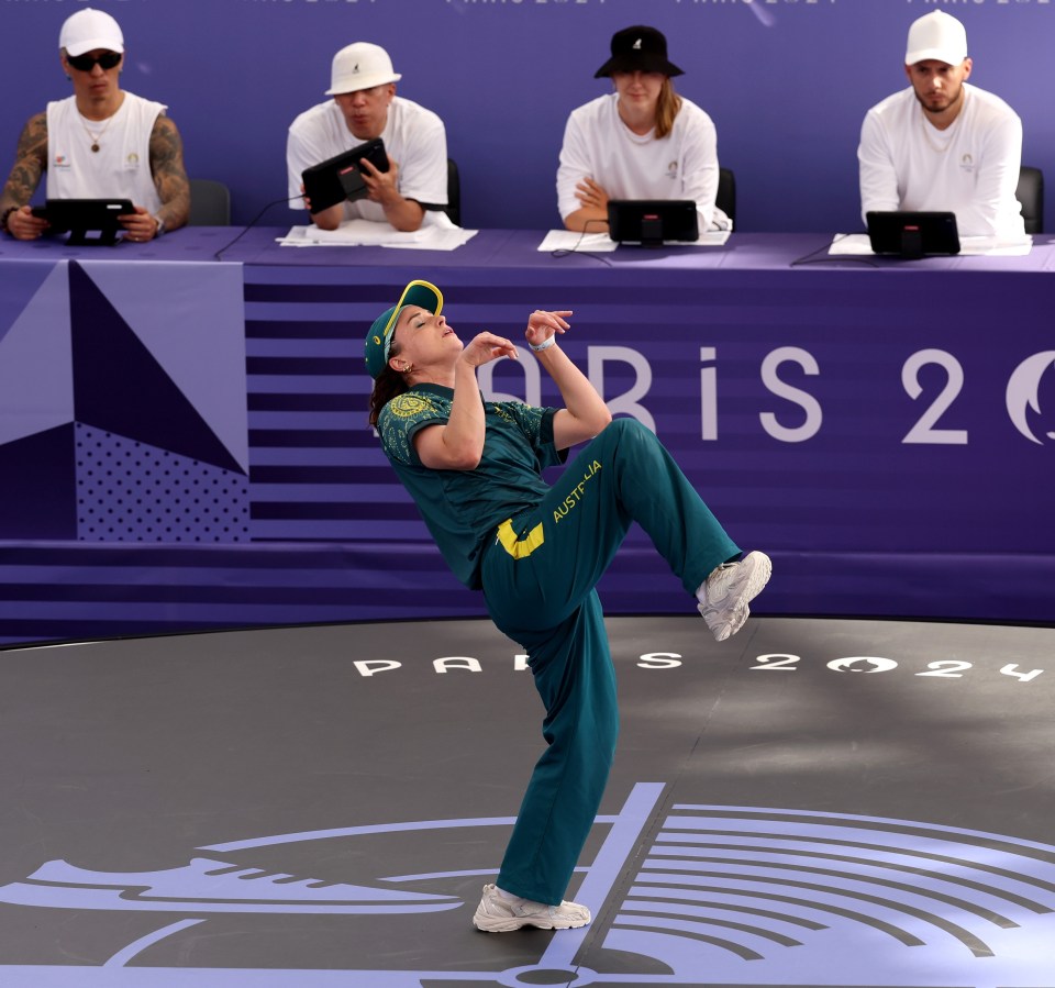 a man performs in front of a paris 2024 sign