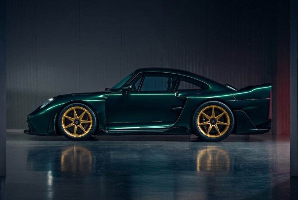 a green car with gold wheels is parked in a dark room