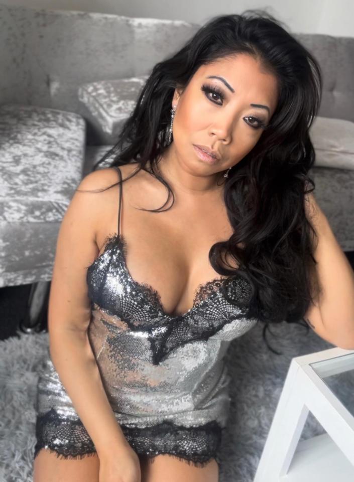a woman in a black and silver dress sits on a couch