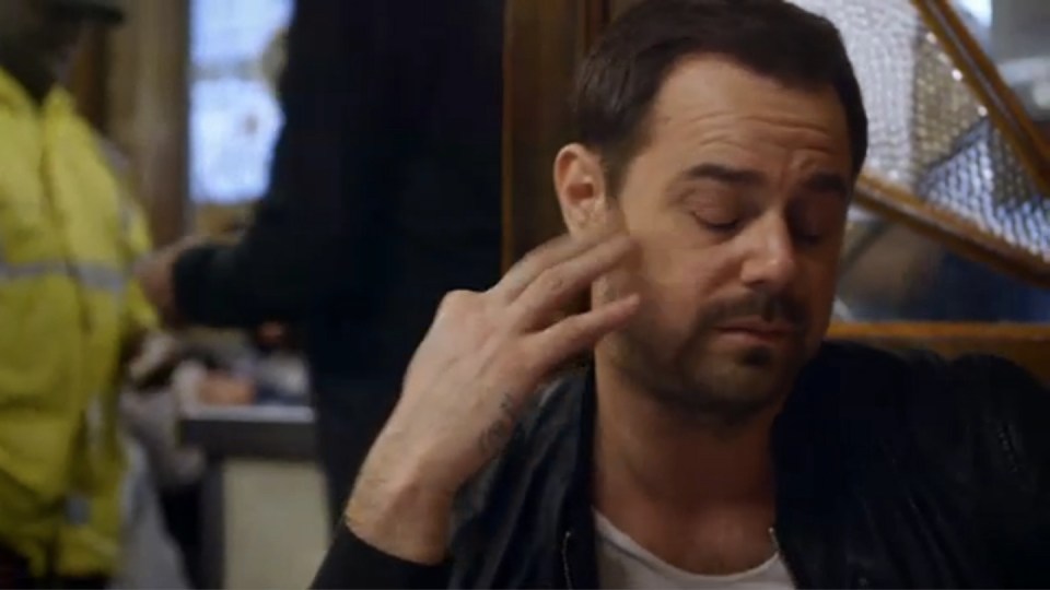 a man is sitting at a table with his eyes closed and his hand on his ear .