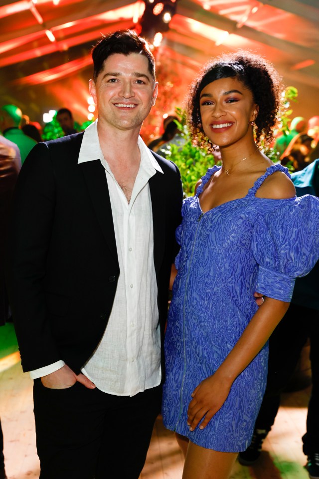 a man in a suit and a woman in a blue dress pose for a picture