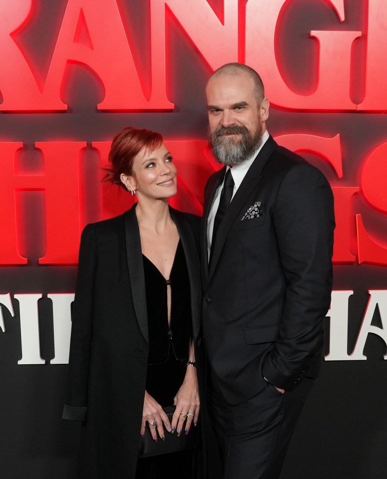 a man and a woman pose for a picture in front of a sign that says stranger things