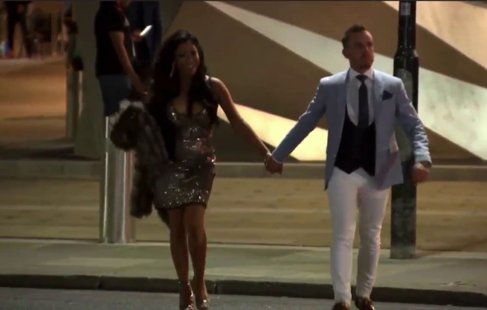 a man and woman walking down the street holding hands