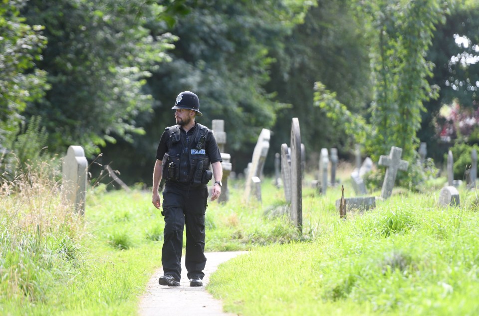 a police officer is walking through a cemetery