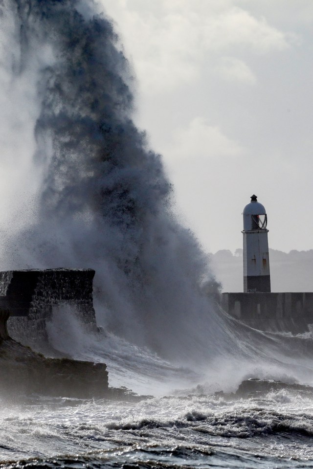 a lighthouse on a pier with waves crashing against it