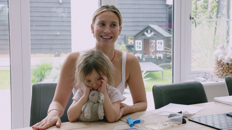 a woman sits at a table holding a little girl