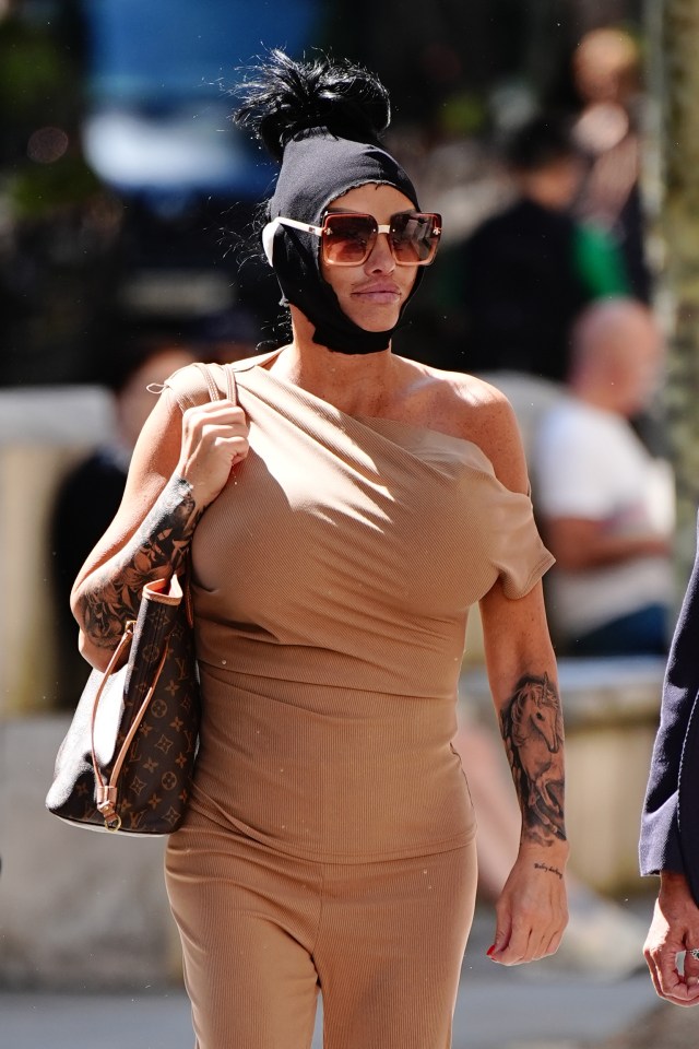 a woman wearing a louis vuitton purse walks down the street