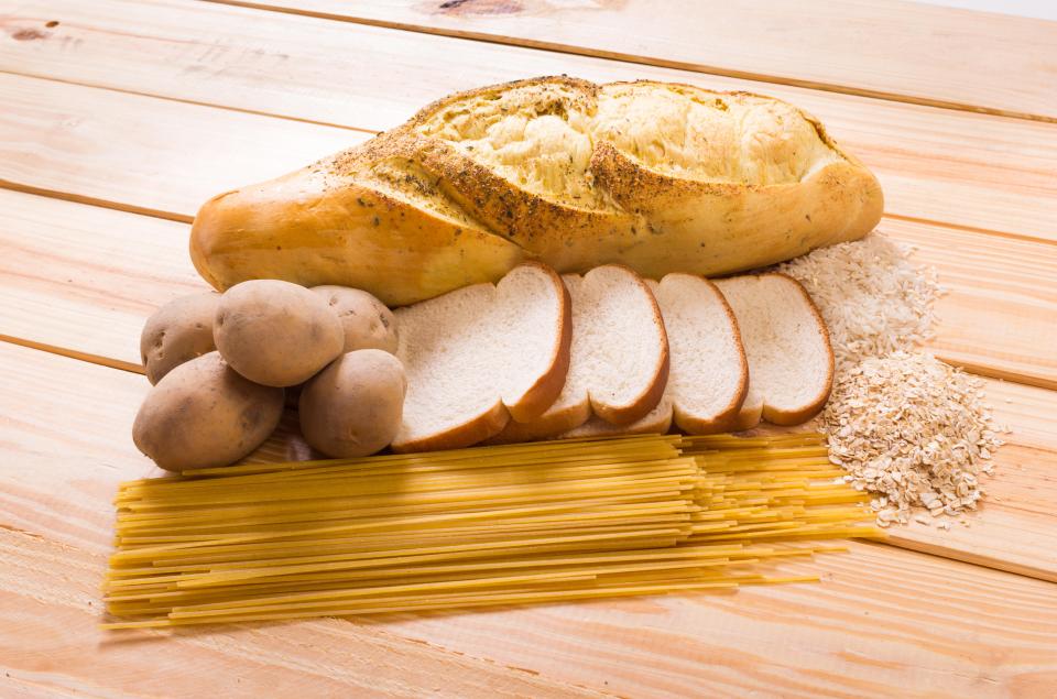 a loaf of bread potatoes and spaghetti on a wooden table