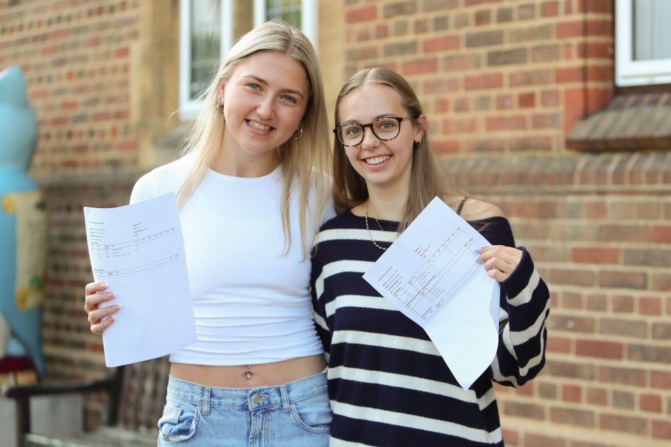 two girls standing next to each other holding a piece of paper