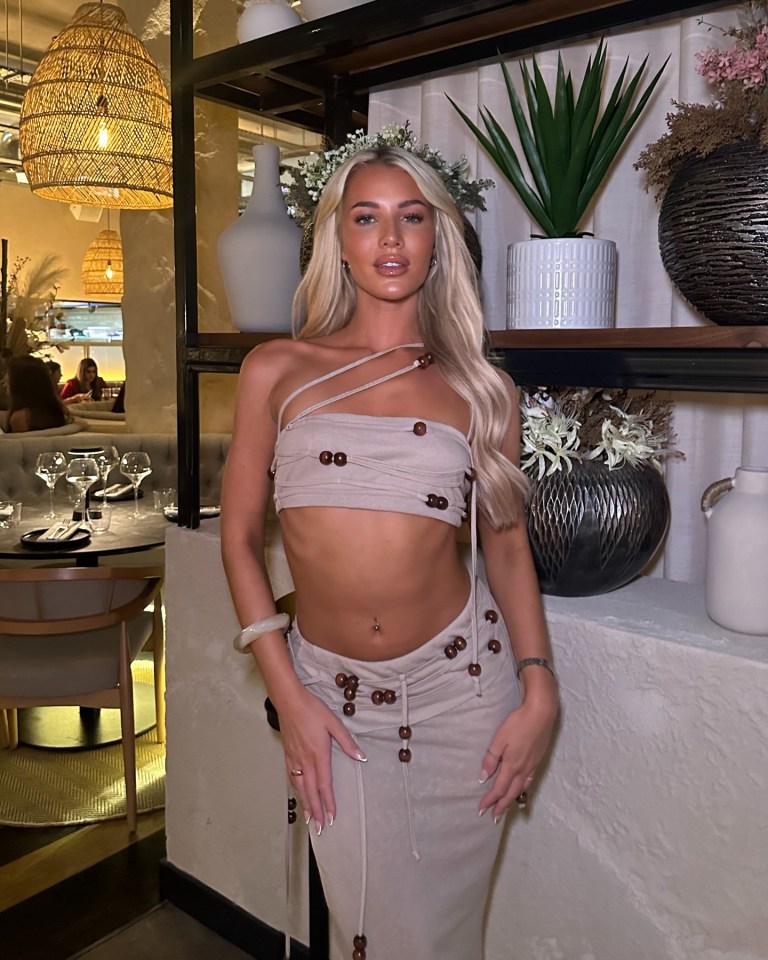 a woman in a crop top and skirt stands in a restaurant