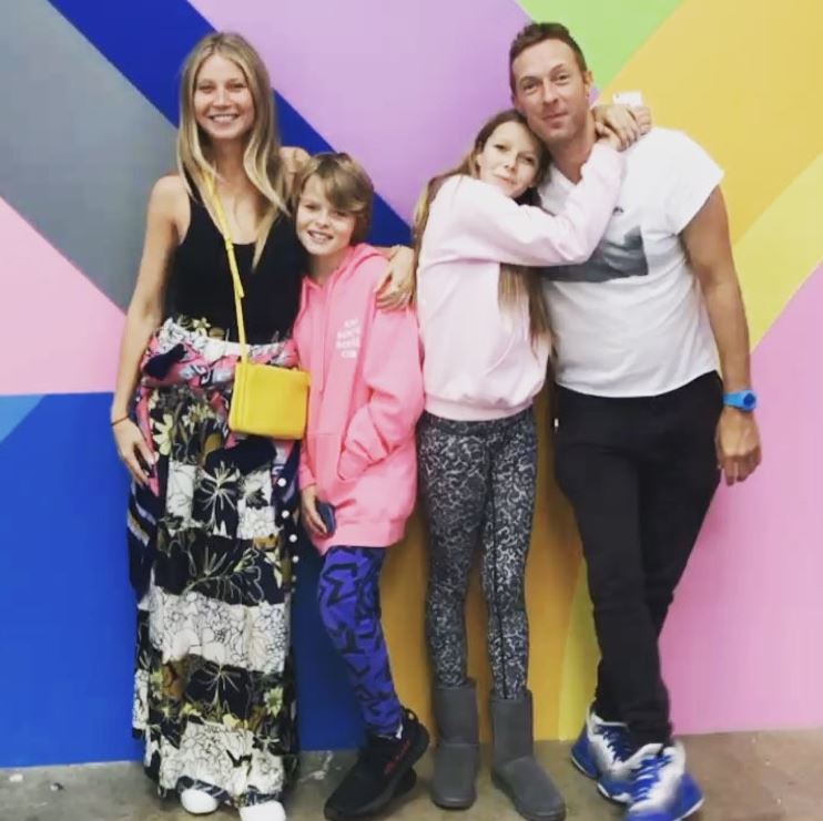 a family poses in front of a colorful wall