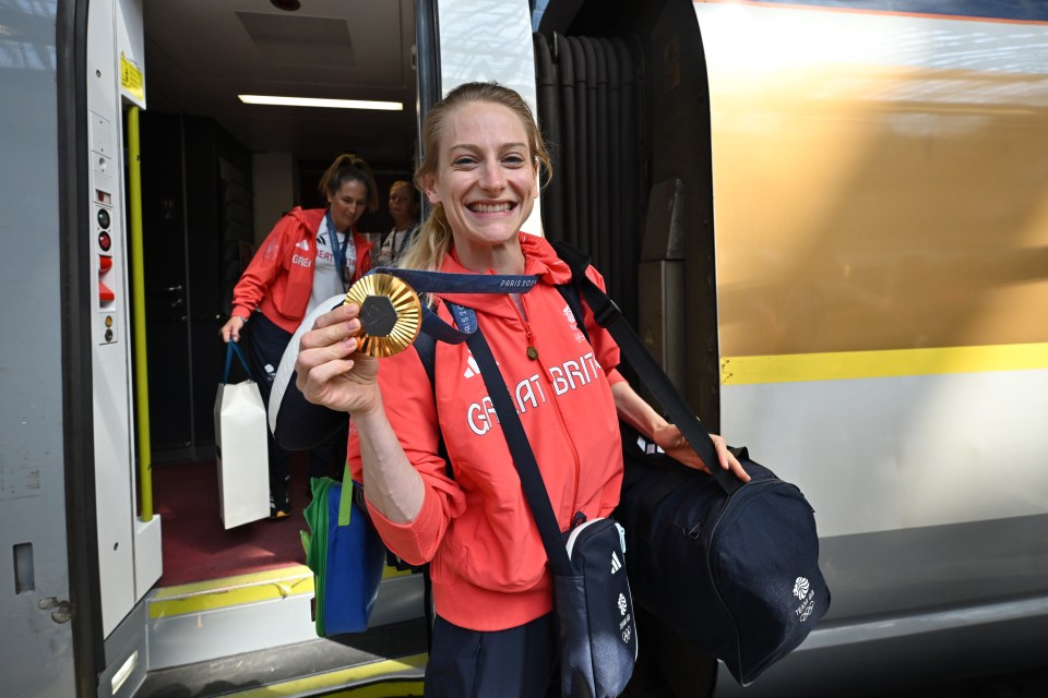 a woman in a red jacket that says great britain holds a gold medal