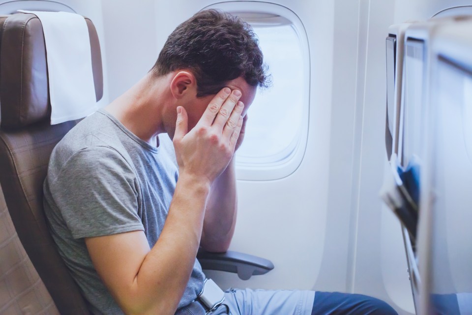 a man sits on an airplane with his head in his hands