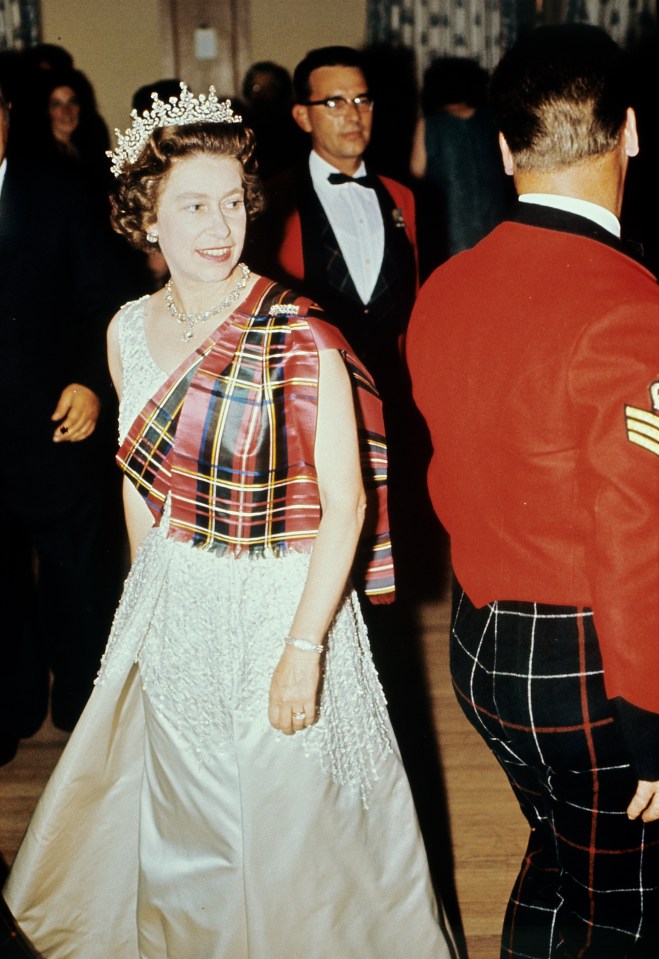 a woman in a white dress with a plaid scarf around her shoulders