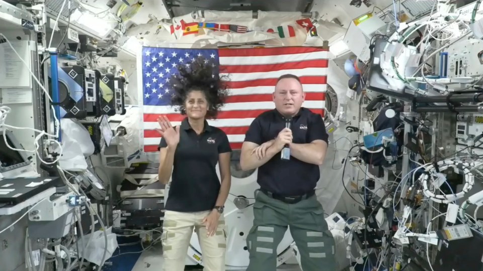 a man and a woman standing in front of an american flag